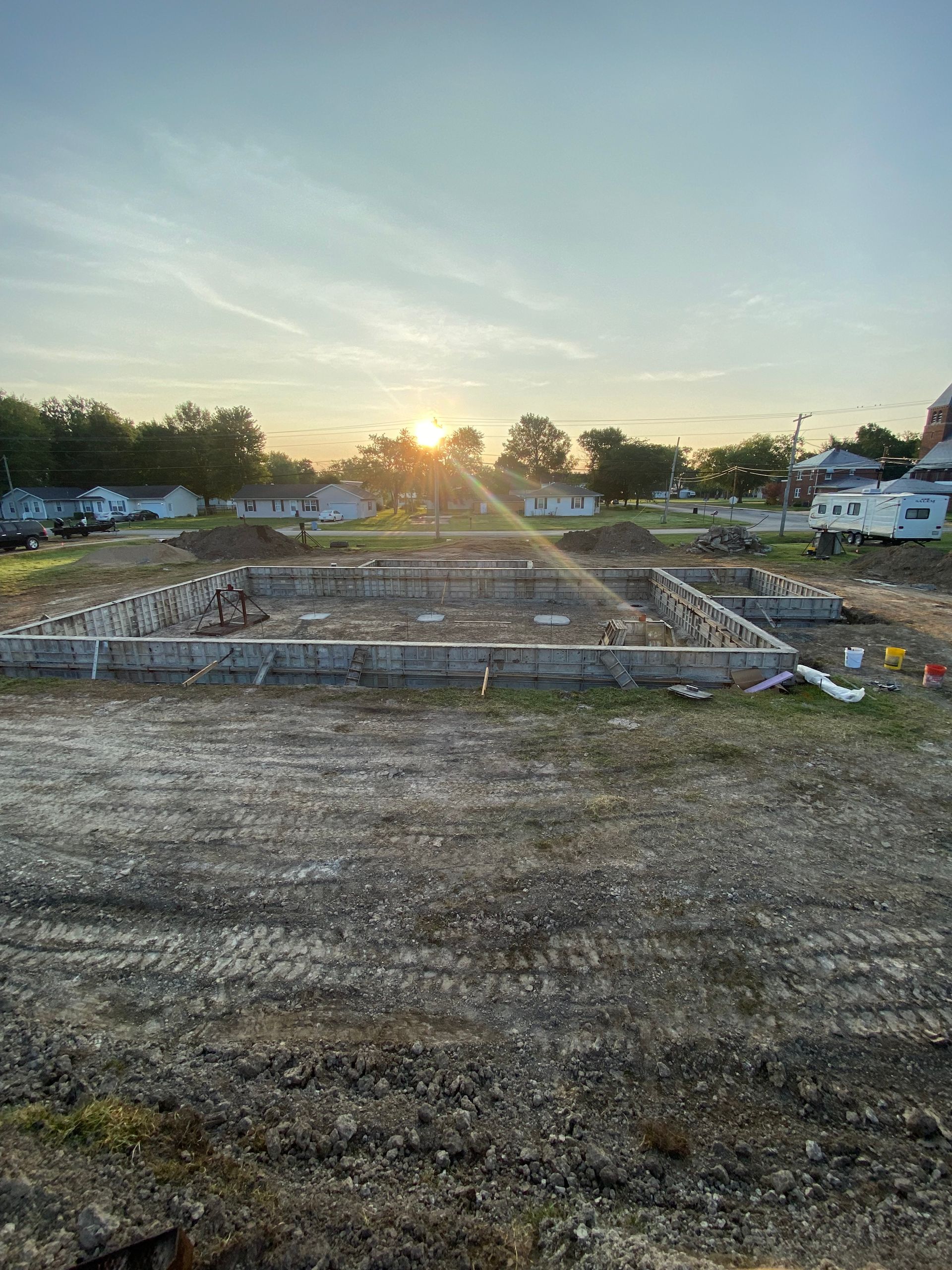 The sun is setting over a construction site with a lot of dirt.