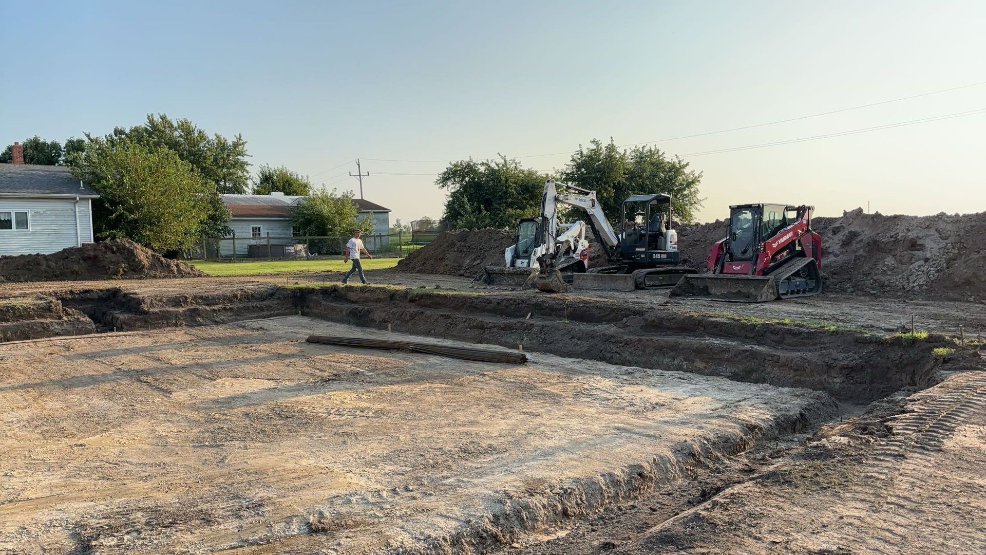 A group of construction vehicles are working on a dirt field.