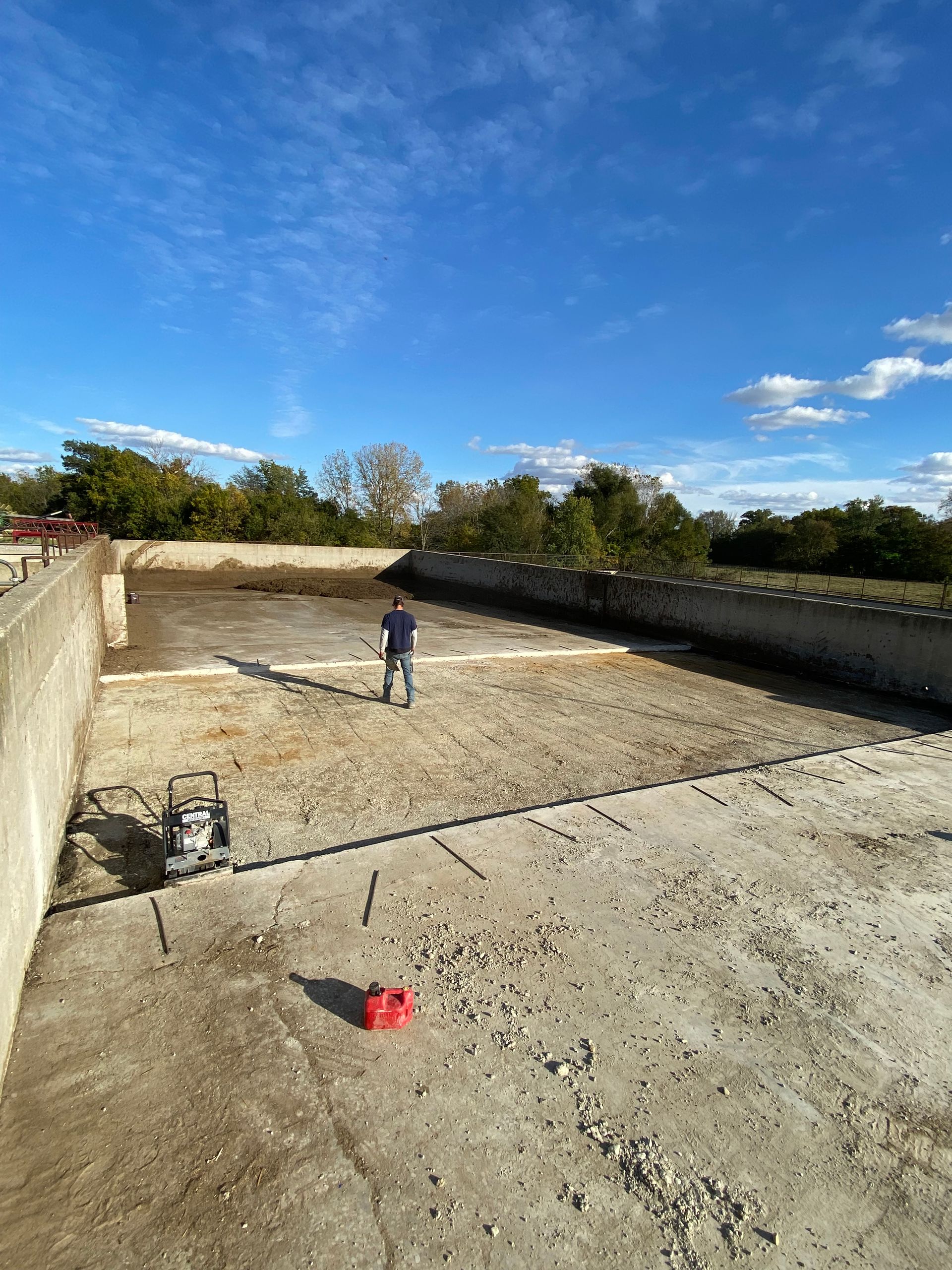 A man is standing in the middle of a large dirt field.
