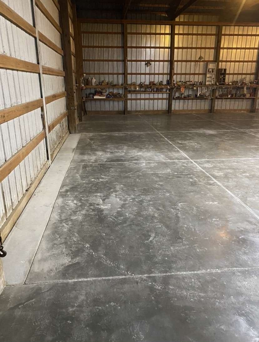 A large empty warehouse with a concrete floor and a wooden wall.