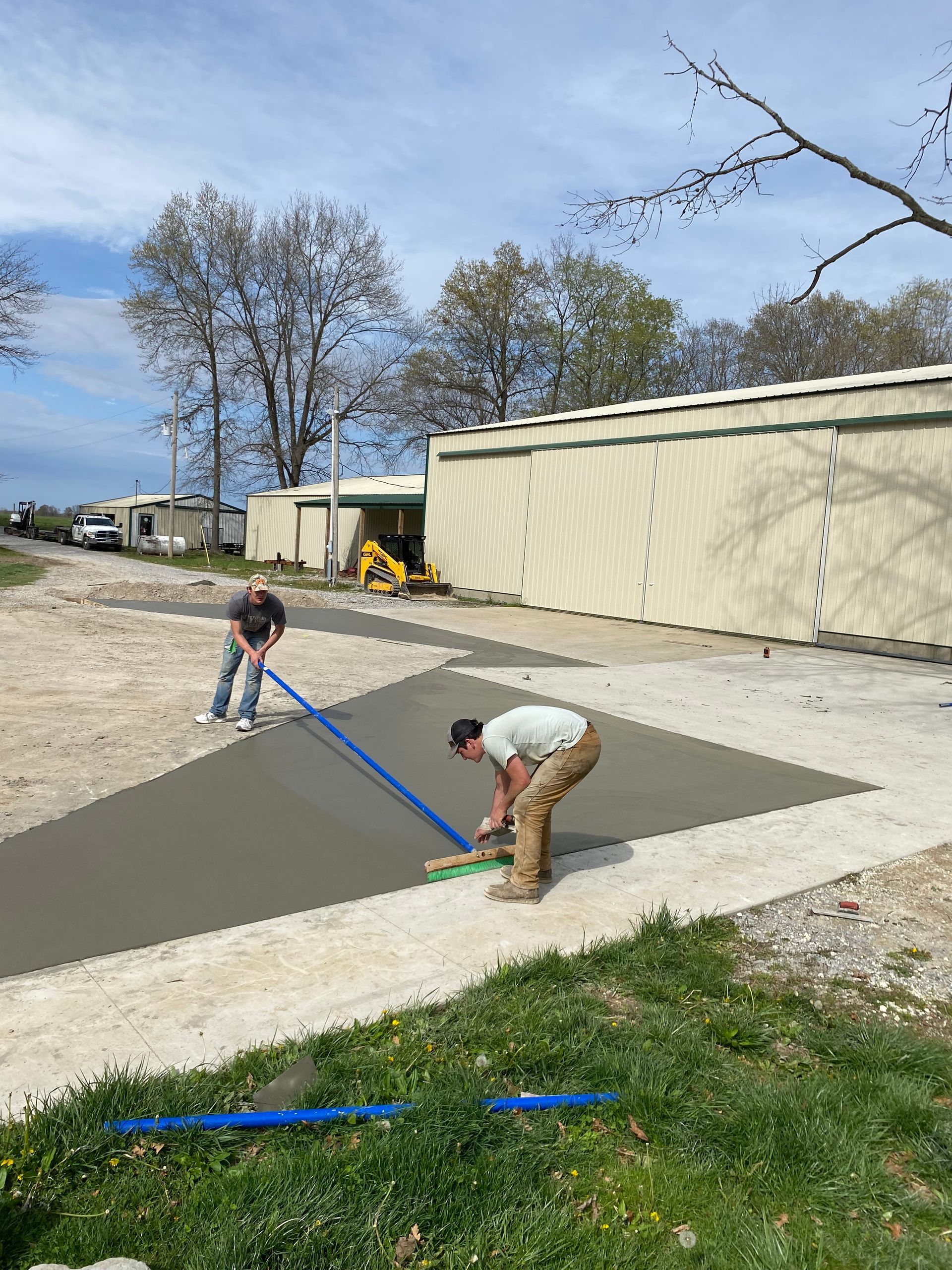 A man is bending over to spread concrete on a sidewalk.