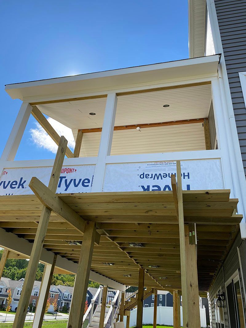 Construction of a porch with wooden frame, under a bright blue sky.