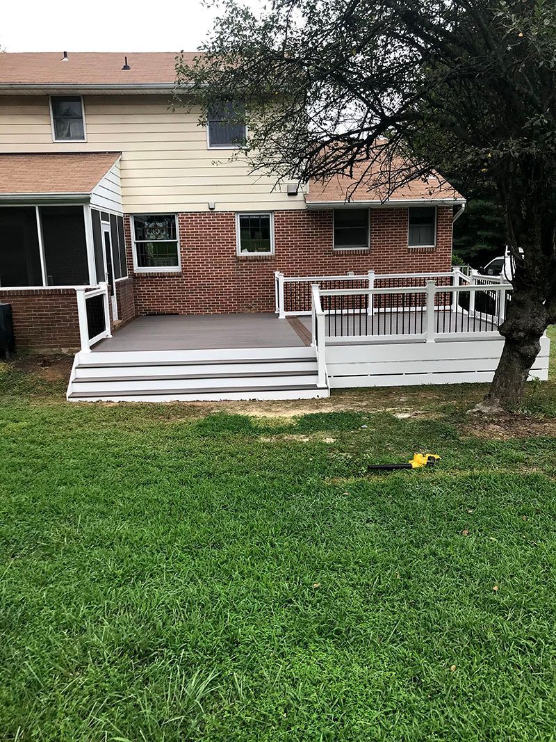 Backyard view with a deck and house; green grass in foreground.