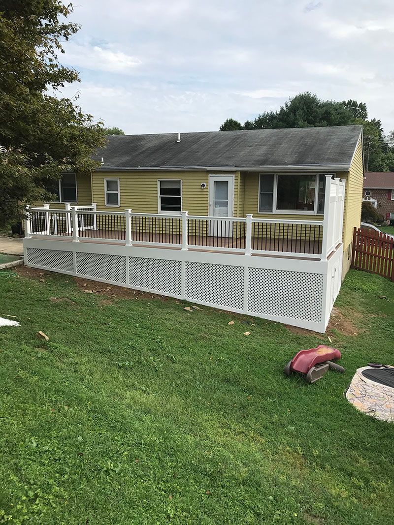 Yellow house with a large white deck; green yard.