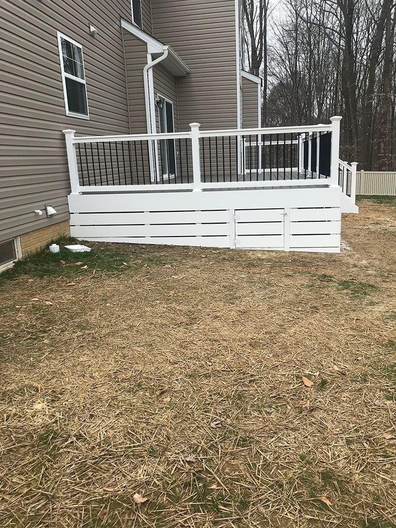 White deck attached to a beige house, overlooking brown grass.
