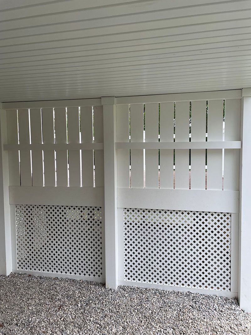 White lattice and vertical slat skirting under a white deck, set on gravel.