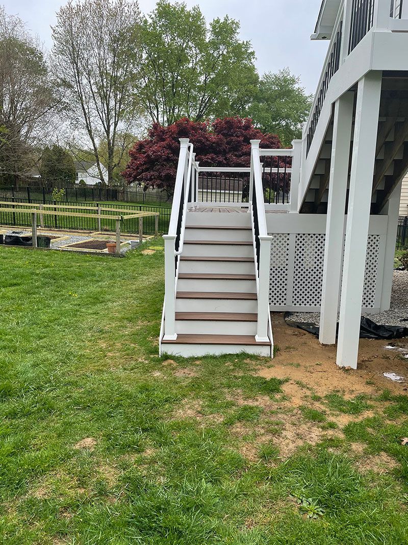 White stairs leading up to a deck, set in a green yard.