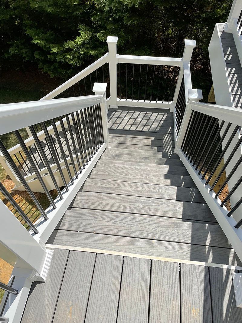 Wooden staircase with white railings and dark spindles, leading down to a yard.