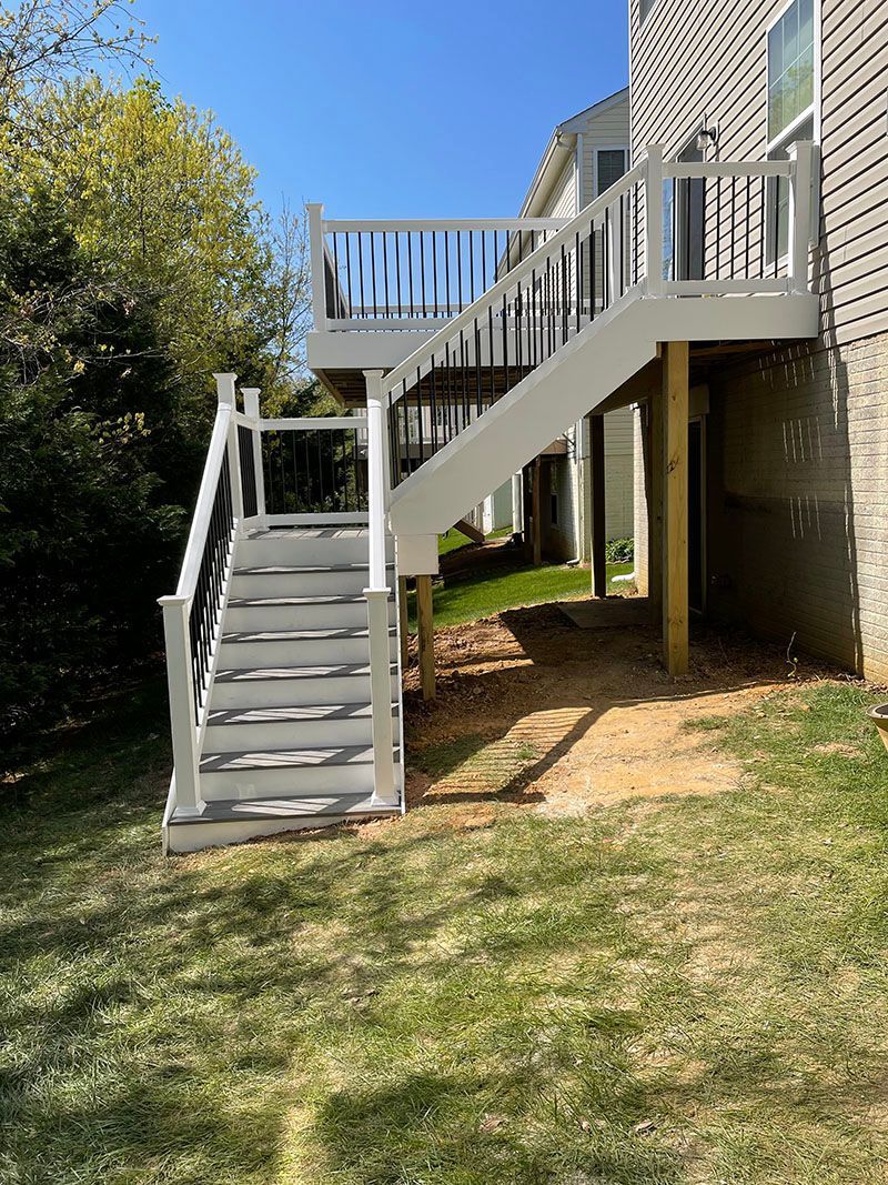 House with two-car garage, SUV in driveway, and for sale sign in the front yard. Green lawn and flower bed.