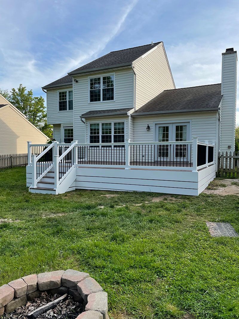 Two-story white house with a deck, backyard, and a fire pit.