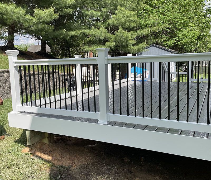 White deck with black railings in a grassy backyard.
