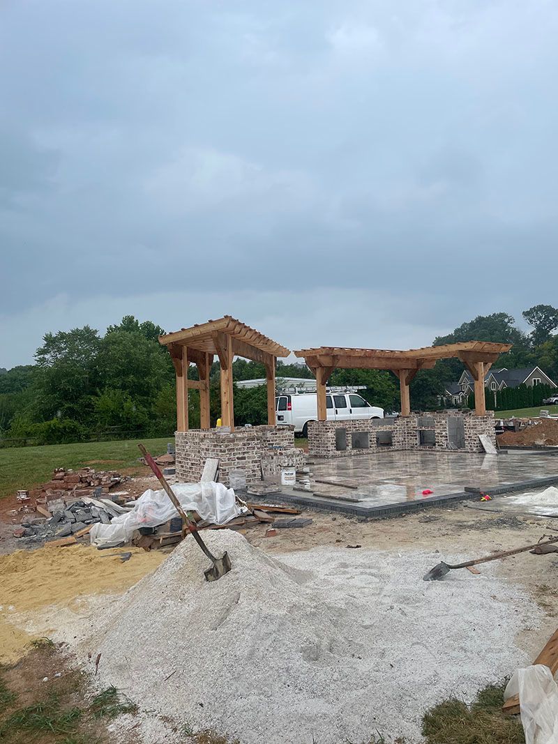 Construction site with wooden pergolas on stone bases, overcast sky.