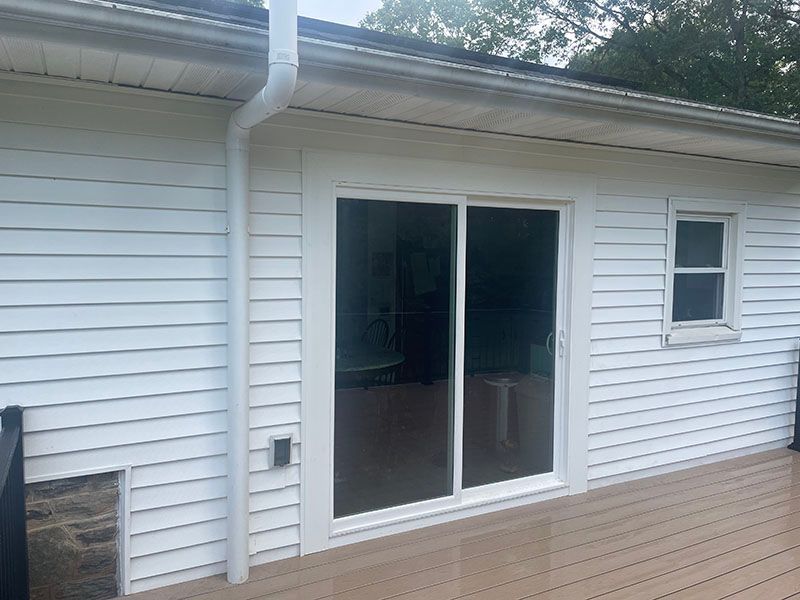 White house exterior with sliding glass door, small window, and deck; white siding.