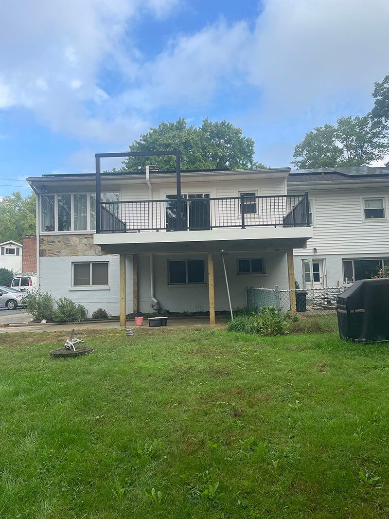 Back view of a two-story house with a partially built deck; green yard.