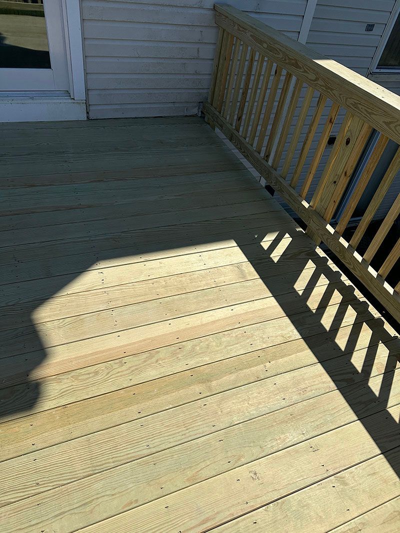 Wooden deck with railing and shadow.