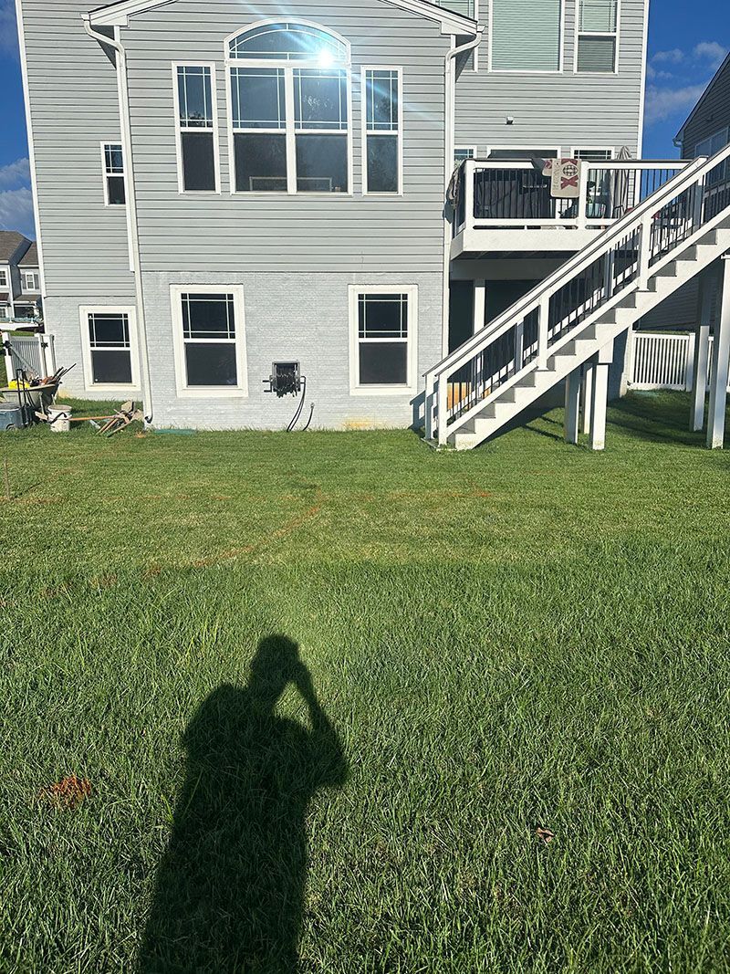 A multi-level deck with stairs next to a house, surrounded by grass and trees.