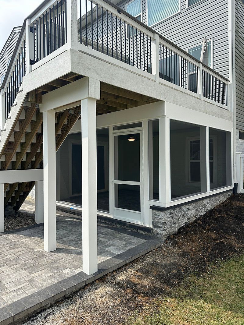White porch with stairs and screened-in area, columns, and patterned pavers.