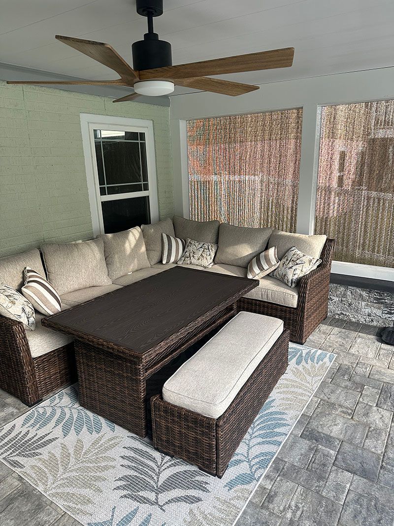 Lounge seating with a brown coffee table and bench on a blue patterned rug, under a ceiling fan.