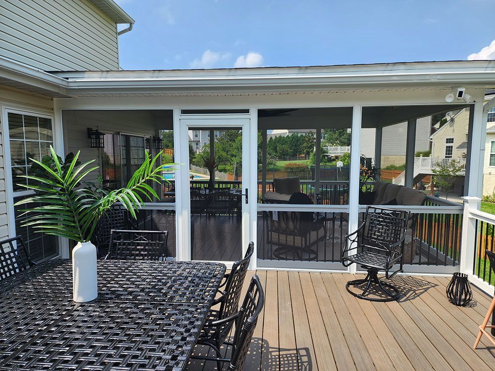 Screened-in porch with outdoor furniture, a view of a yard, and an attached deck.