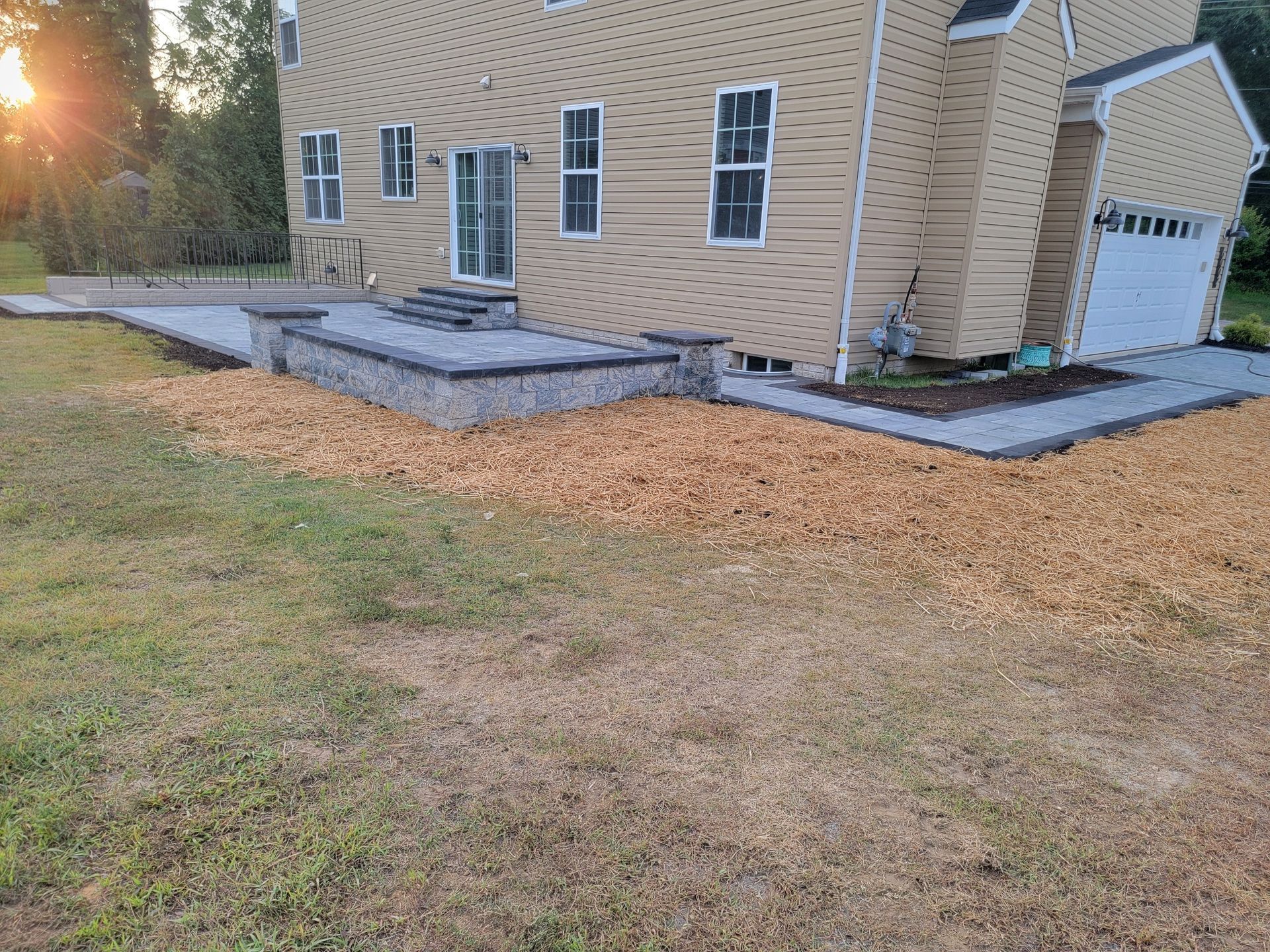 Beige house with patio and woodchip border on grass.
