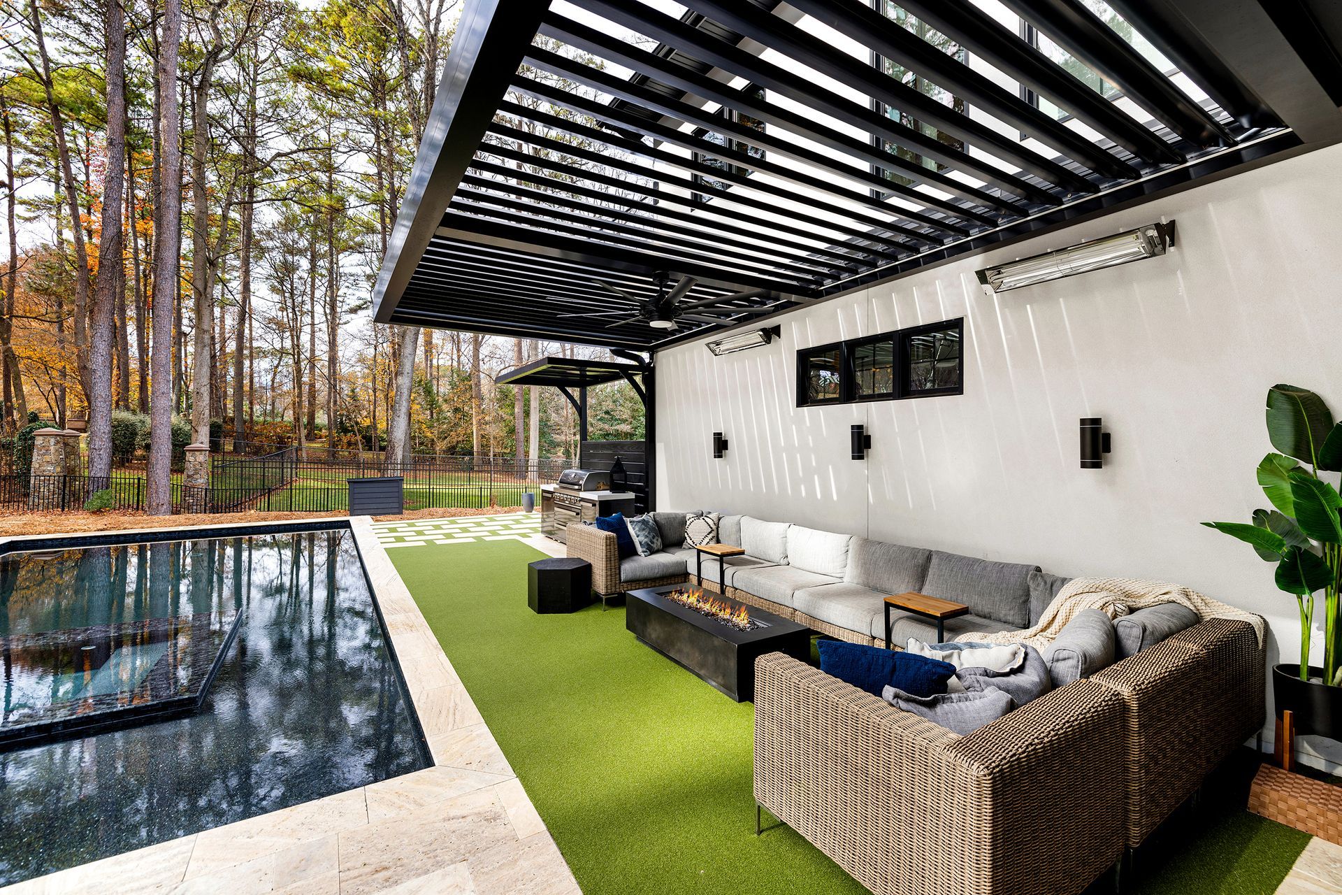 Outdoor living space with pool, pergola, seating, and green turf.