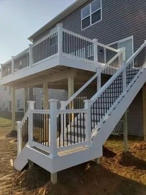 Multi-level deck with white railing and black spindles, attached to a house.