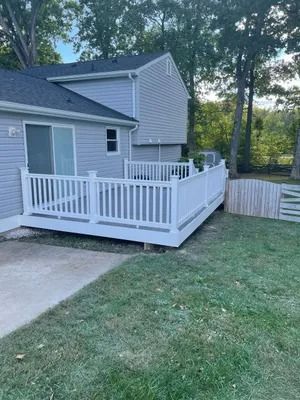 White deck attached to a two-story gray house, overlooking a green lawn.