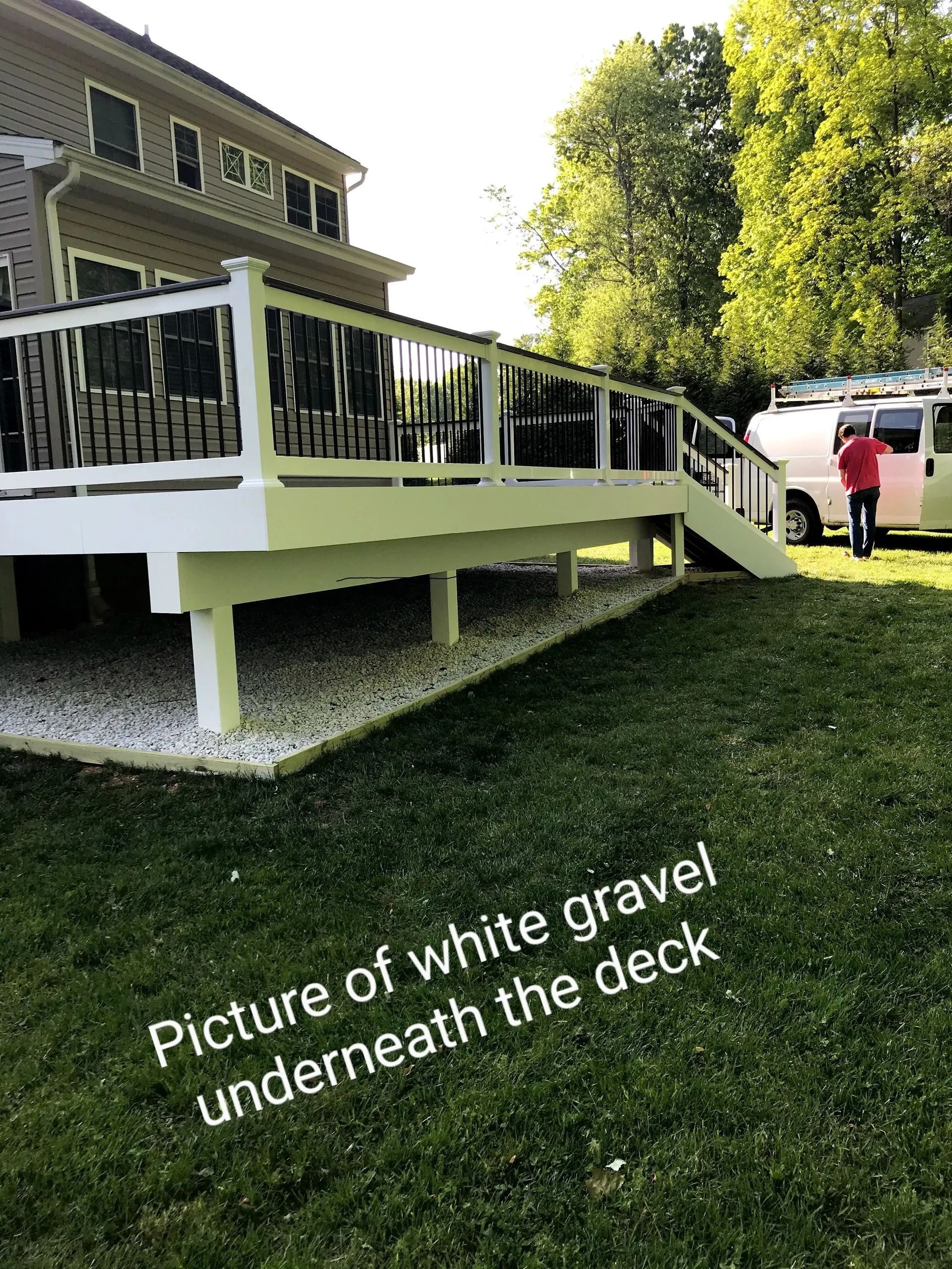 White deck with white gravel underneath. Person stands near a white van.