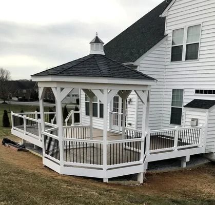 White gazebo and deck attached to a white house, with black railings and a black roof.