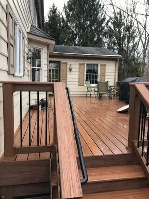 Wooden deck with ramp, railing, and access to building with door and window.