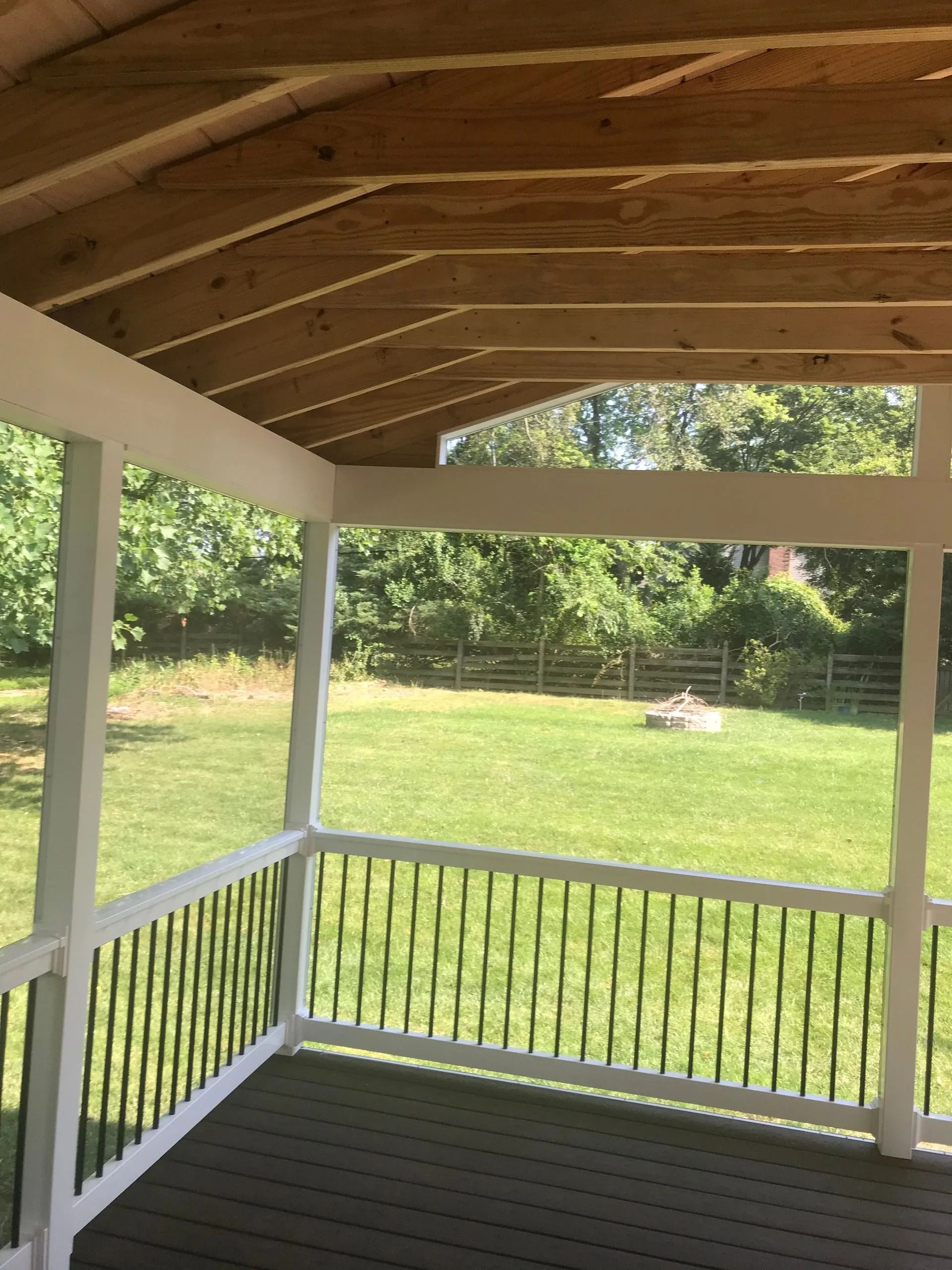 Screened-in porch with white trim, black railings, and a grassy backyard view.