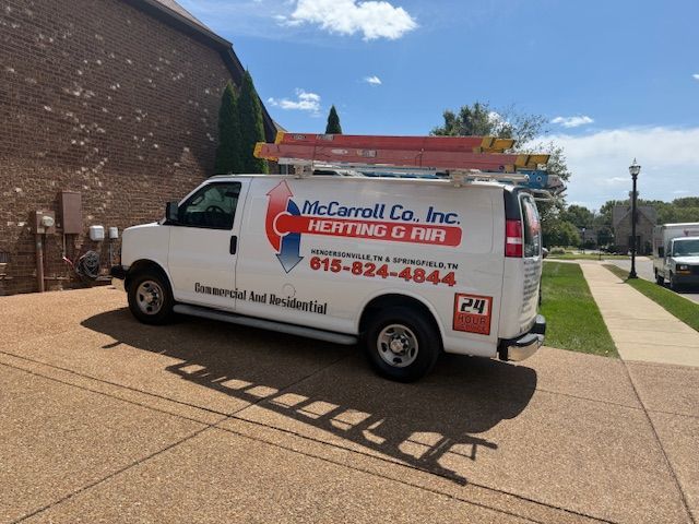 White McCarroll Co. Inc. heating and air van parked on a driveway, with ladders on top.