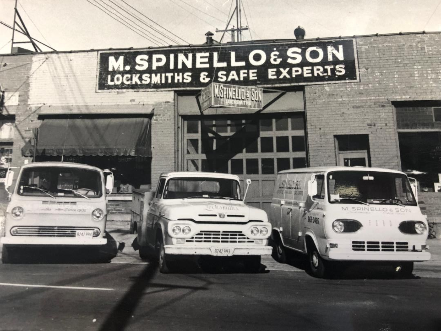 M. Spinello & Son Locksmiths storefront with three vans parked in front. Sign reads 