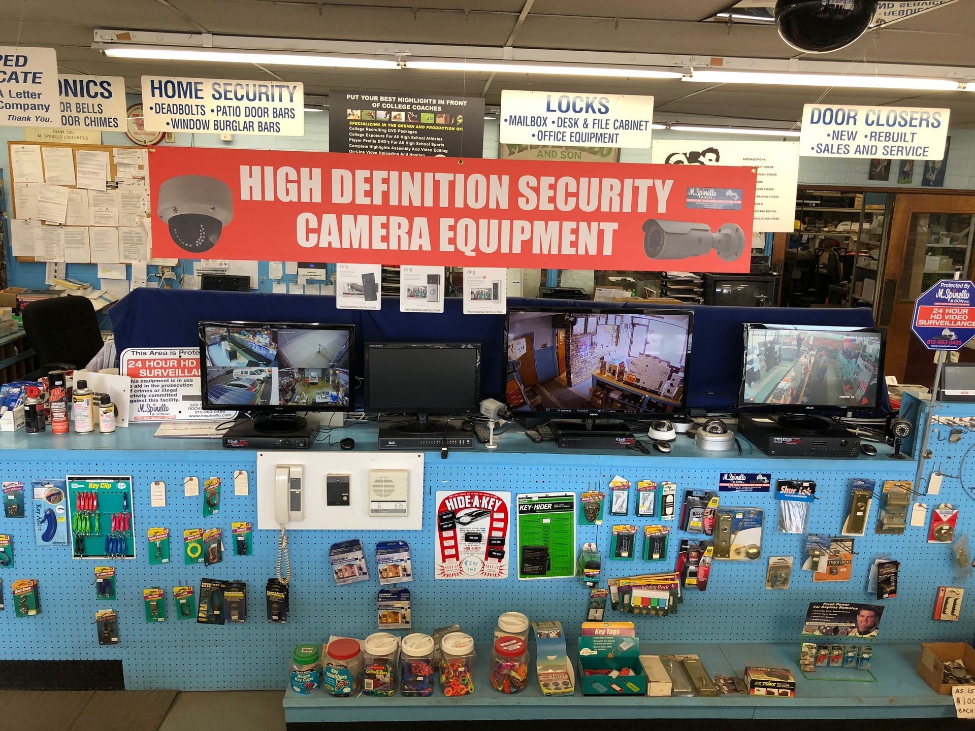 A store display of security camera equipment, with monitors, cameras, and various hardware, under a banner.