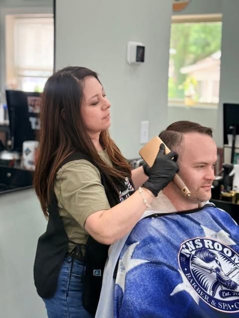 Hairdresser trimming a client’s hair in a salon, with the client wearing a blue cape.