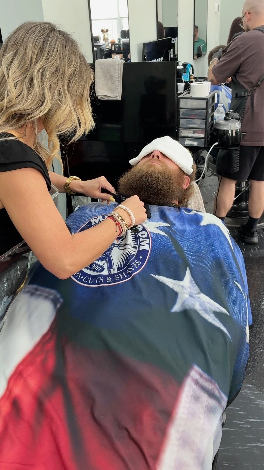 Hair salon stylist working on a client draped in a Texas flag cape
