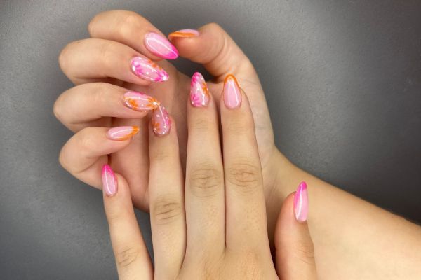 Hands with pink and orange gradient nail design.