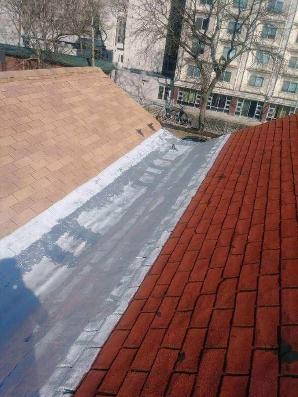 A red brick roof with a white gutter and a building in the background