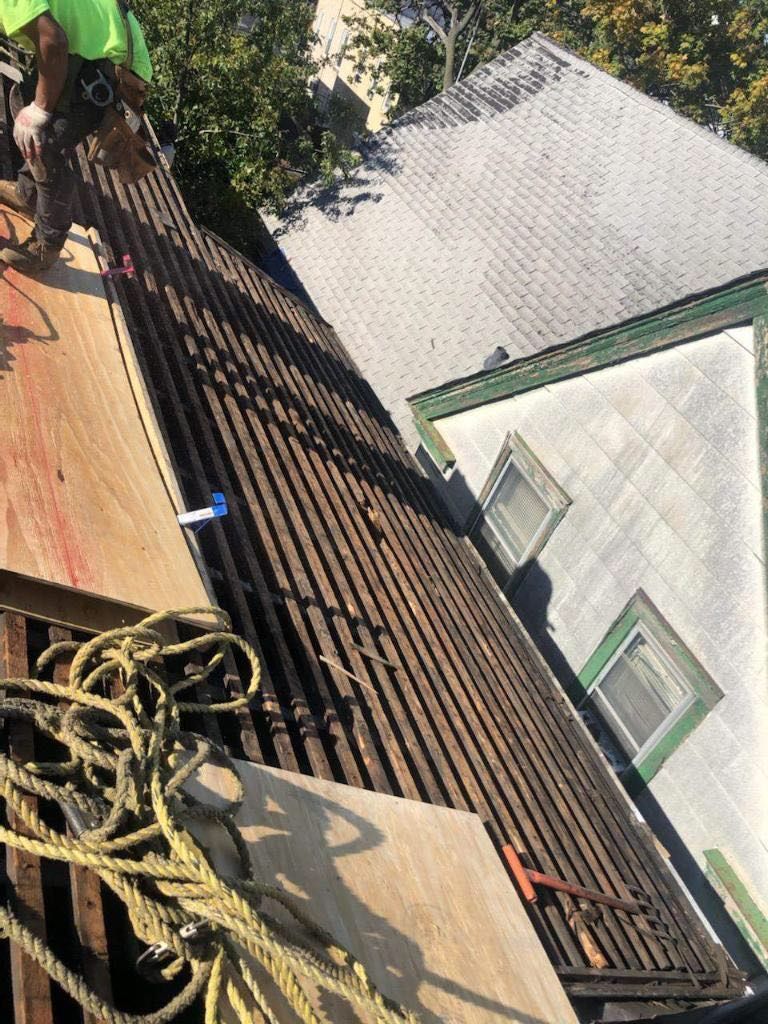 A man is standing on top of a wooden roof.