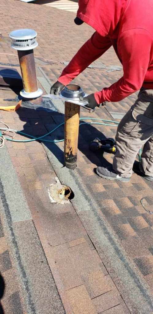 A man in a red hoodie is working on a roof.