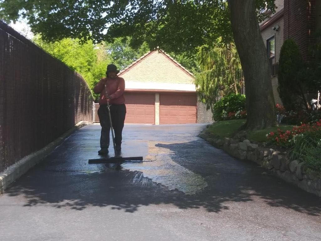A man is cleaning a driveway with a broom