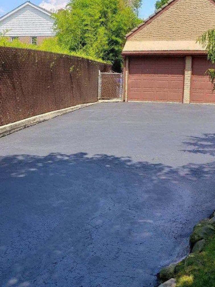 A driveway with a fence and a garage in the background.