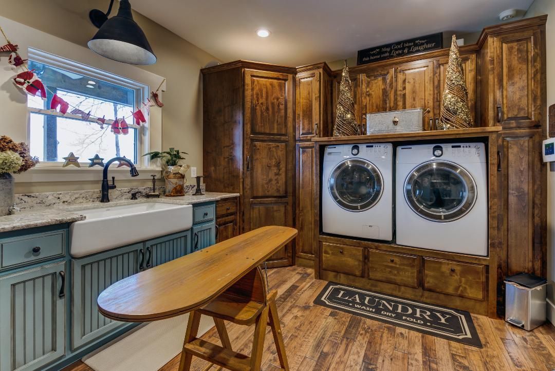A laundry room with two washers and dryers and a wooden table.