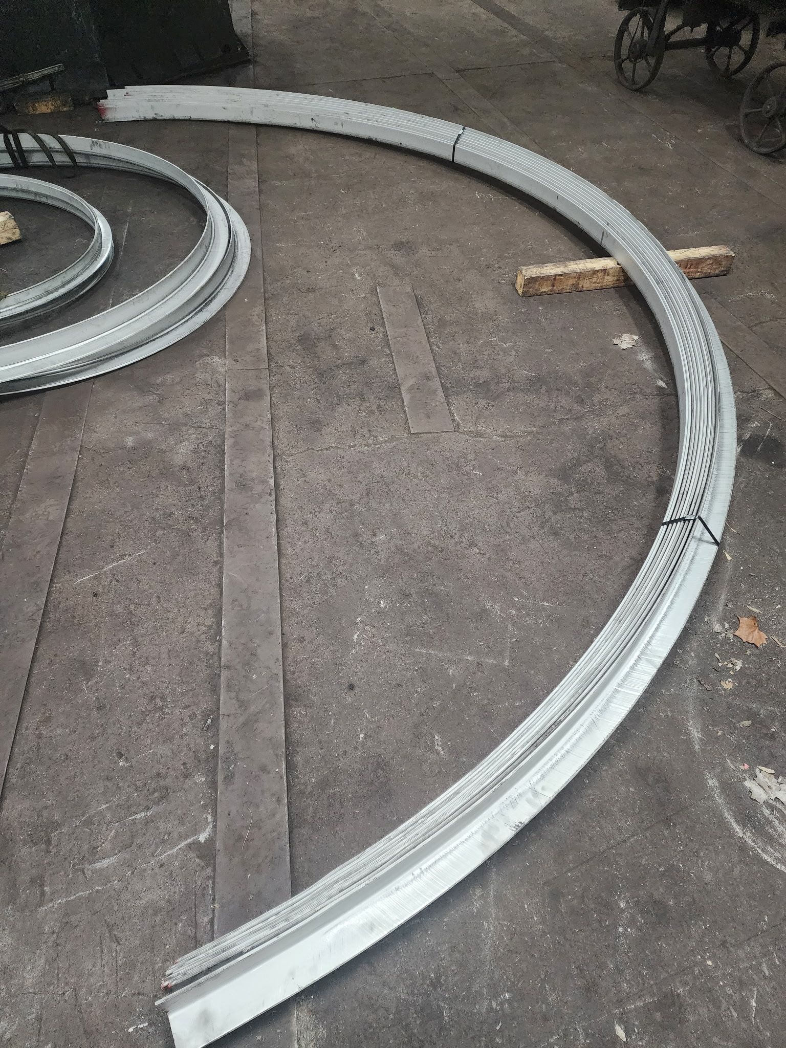 Curved metal track sections on a concrete surface, possibly for a railway or industrial setup.