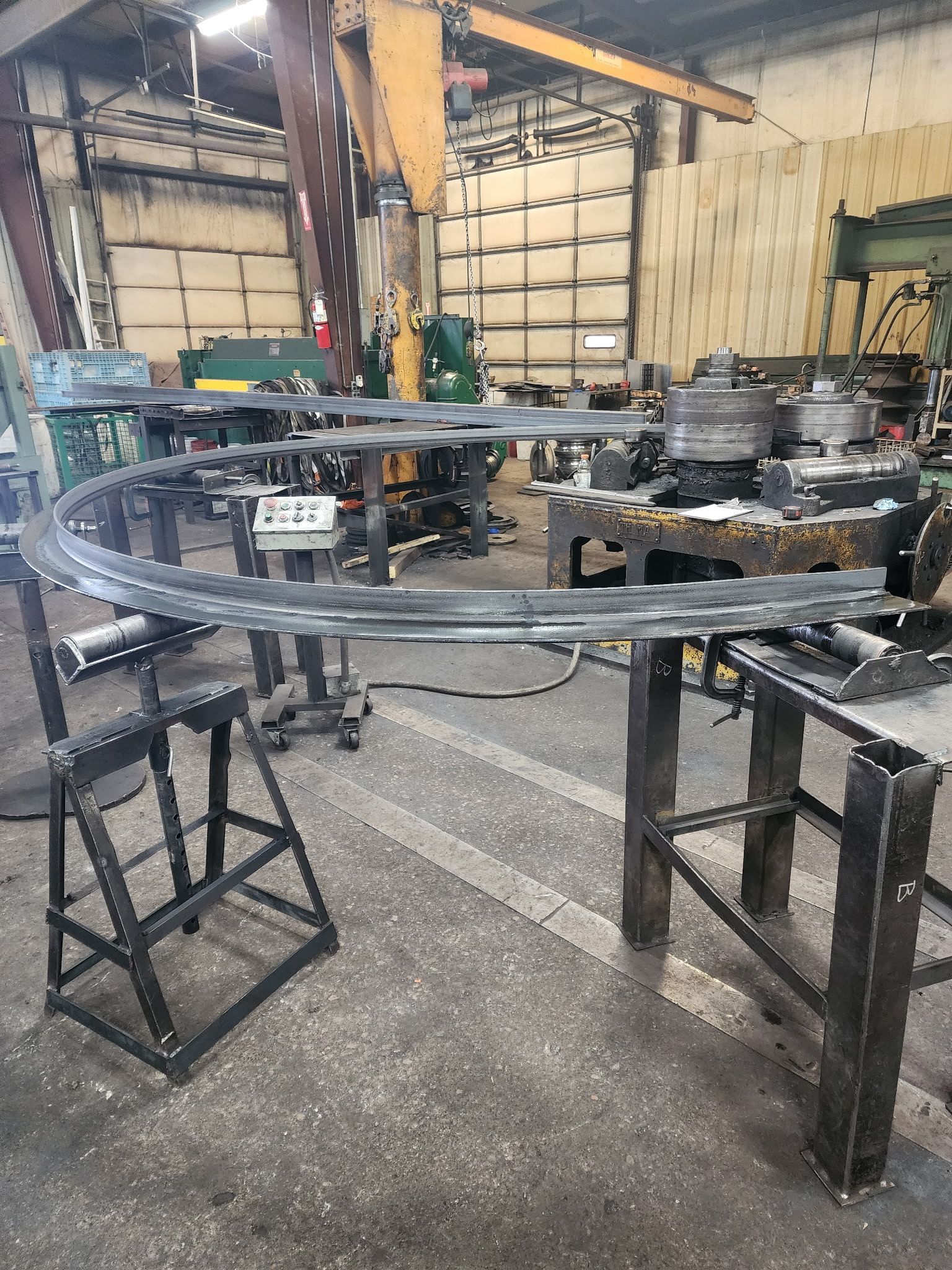 Steel ring structure in a workshop; ladder and metal tables in foreground.