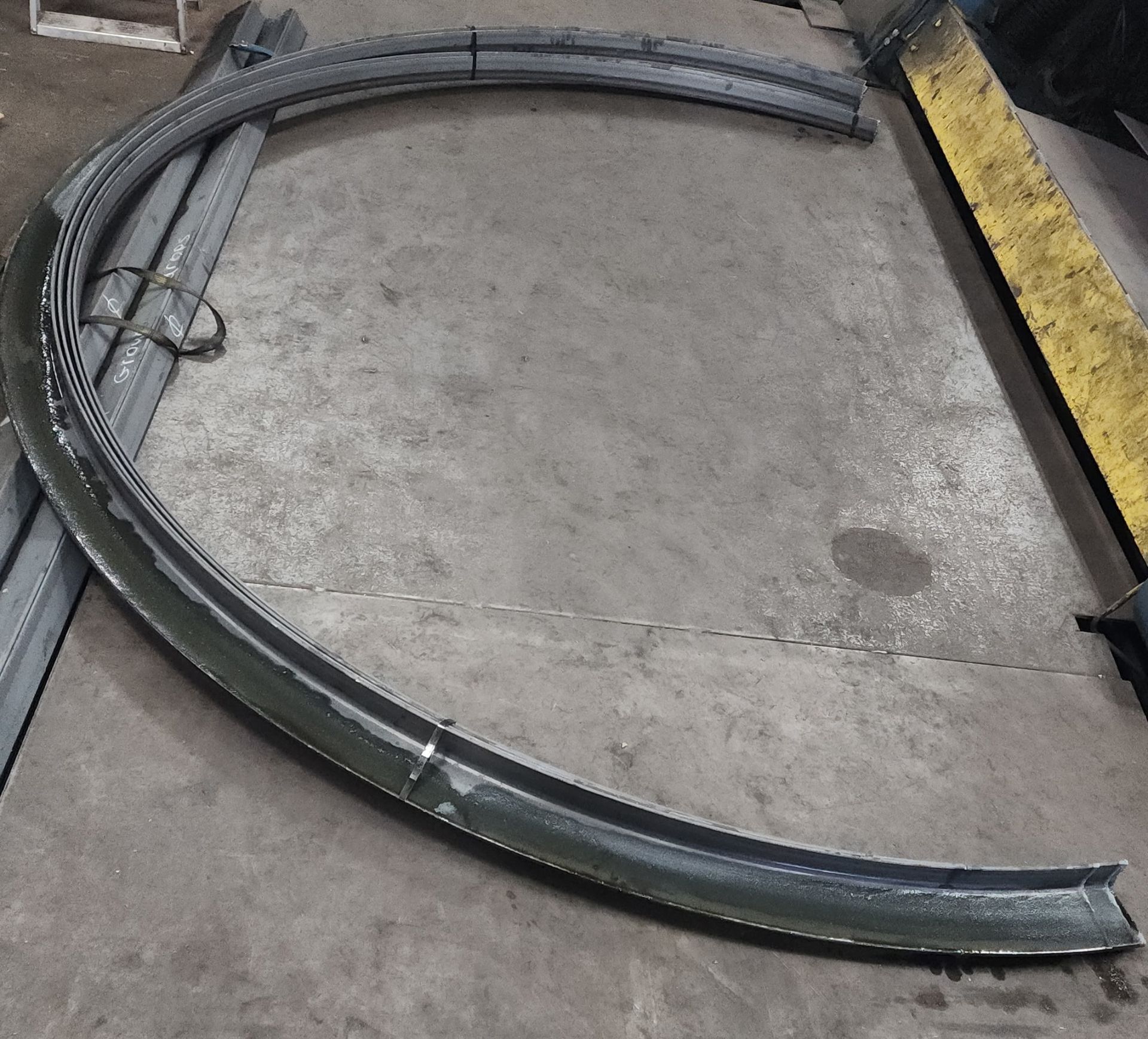 Curved steel beam on a concrete floor in a workshop.