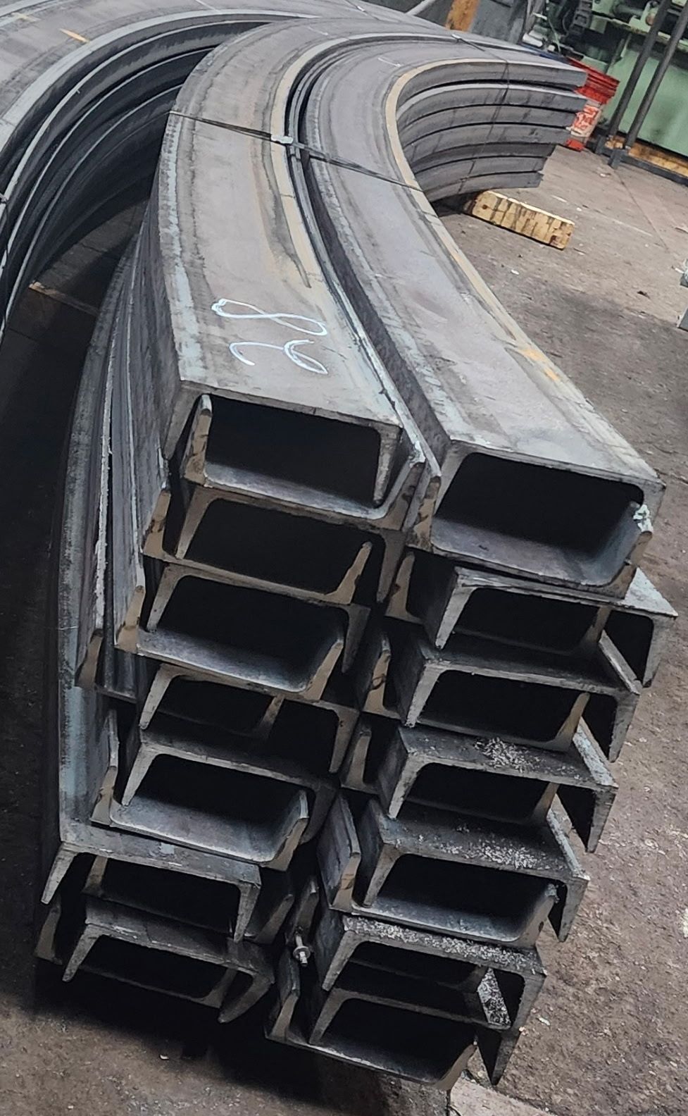 Curved steel beams stacked, ready for construction.