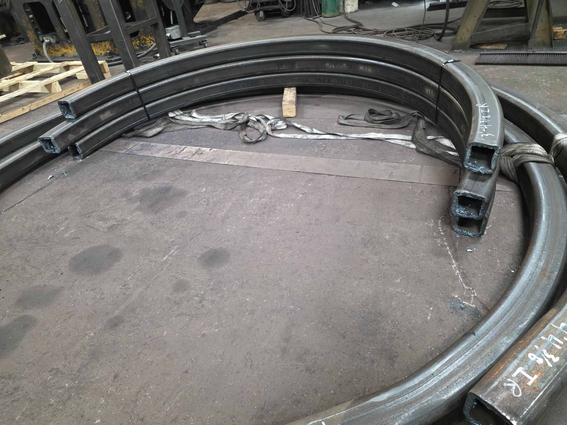Curved metal tubes, likely steel, stacked on a gray workshop floor.