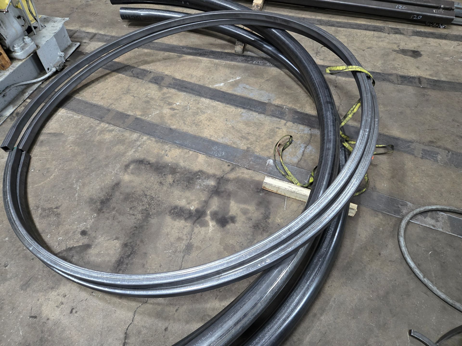 Curved metal rails bundled on a gray concrete floor.