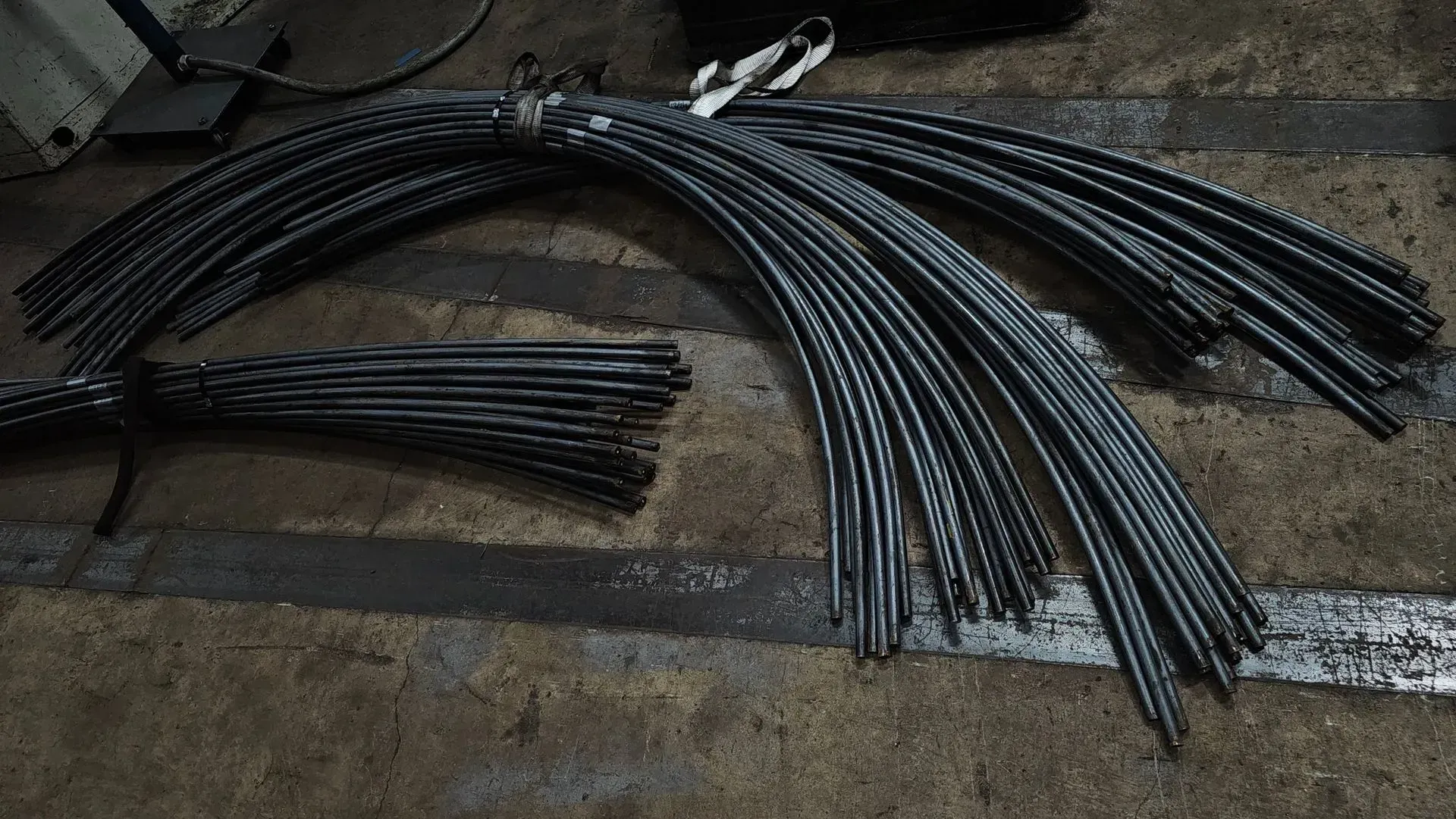 Bundles of curved, black rebar on a concrete floor.